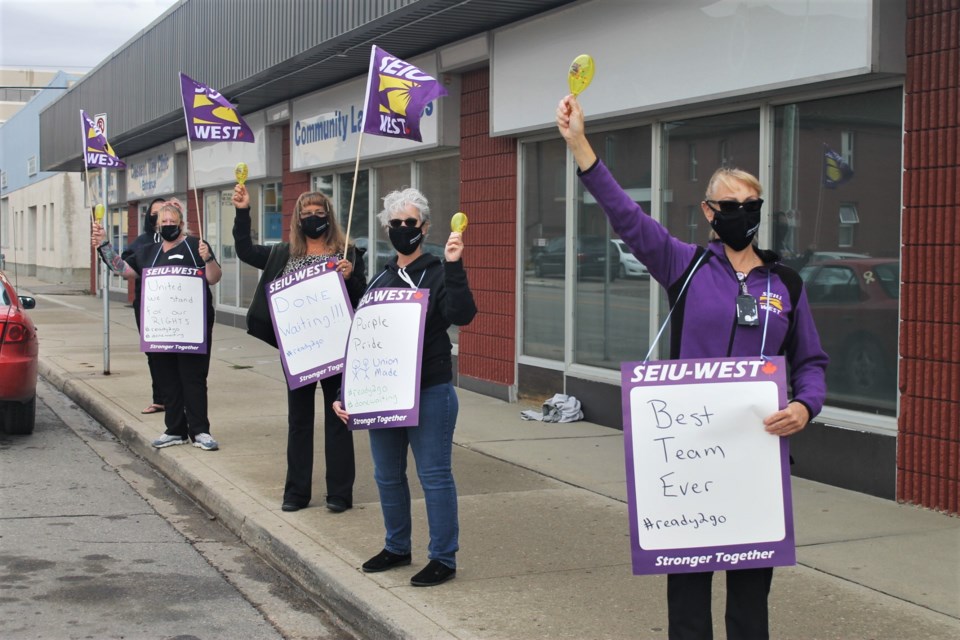 SEIU-West members outside of Crescent View Clinic in Moose Jaw, each wearing a different sign in support of their union.