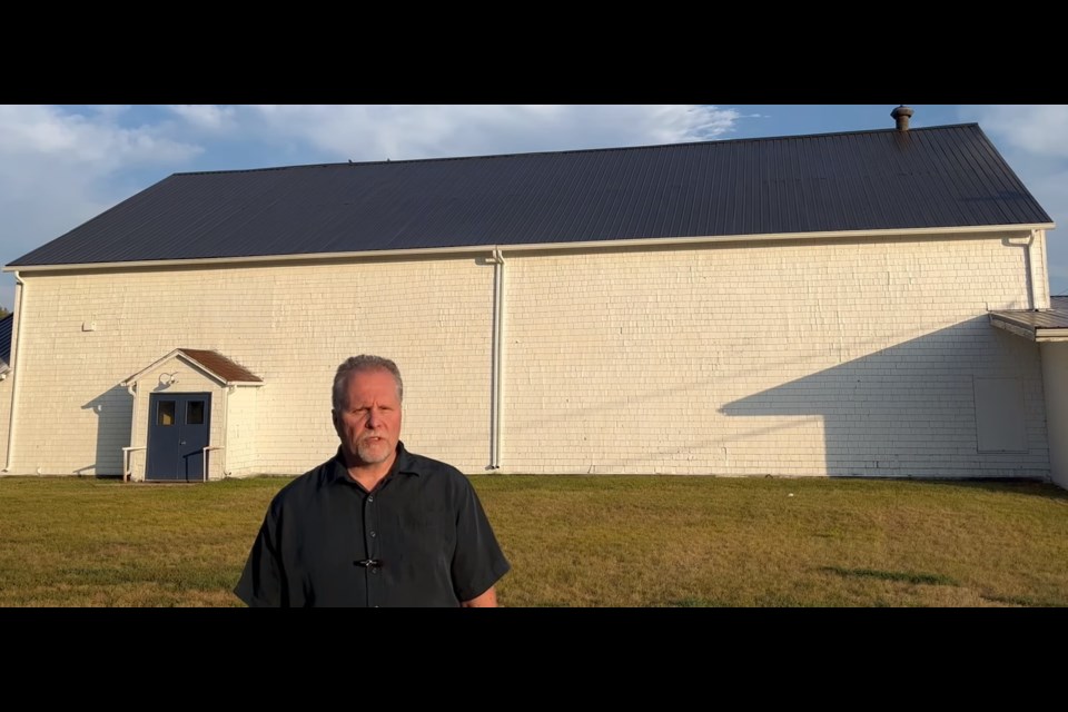 A screenshot from a video honouring the former Caron airbase shows Briercrest College professor Joel From speaking in front of a former airbase hangar. Photo by Jason G. Antonio