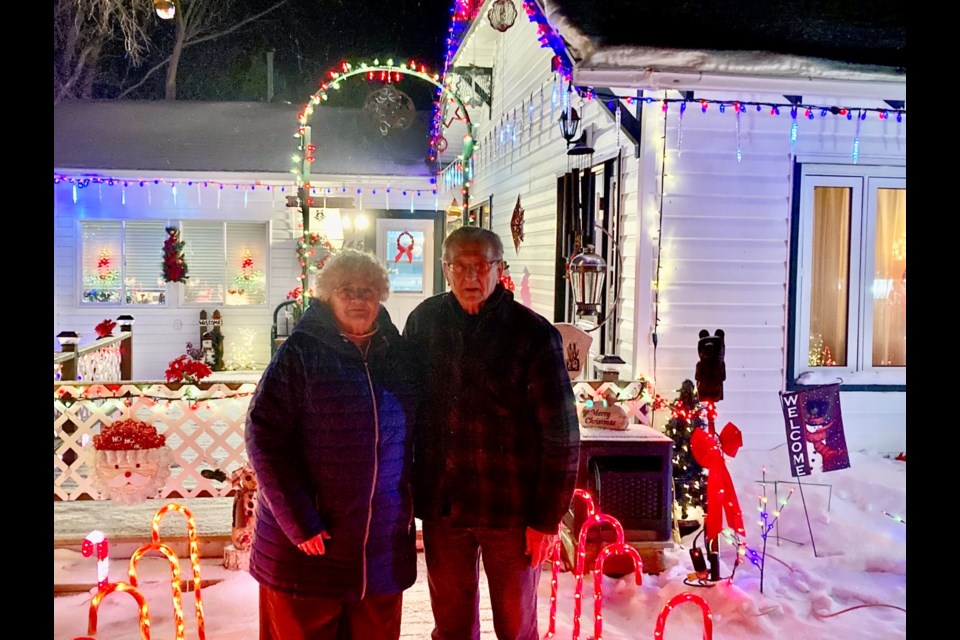 Doreen and Michael Worotniak stand in front of their house in the Village of Brownlee, which they have decorated with many Christmas lights that can be seen from the highway. Photo courtesy Lee Halladay 