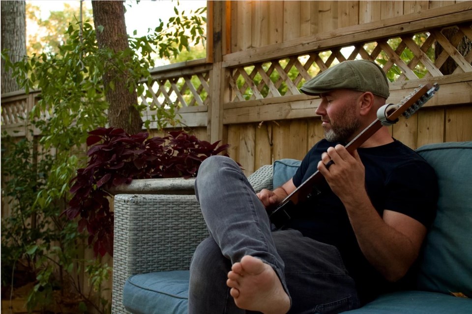 Musician Kurt Buchanan on his guitar in his backyard. Photo courtesy kurtbuchanan.com