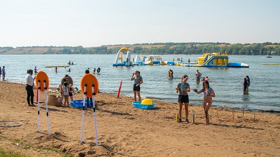 People enjoying the fun beach activities with the Aquatic Adventures obstacle course in the background.