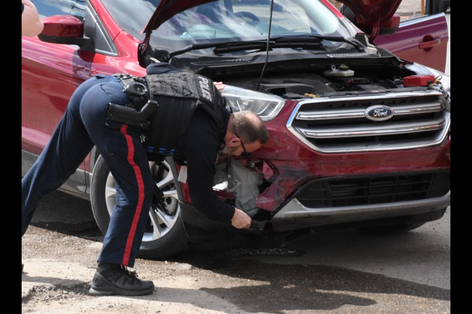 A police officer checks out the damage on the SUV. Photo by Jason G. Antonio