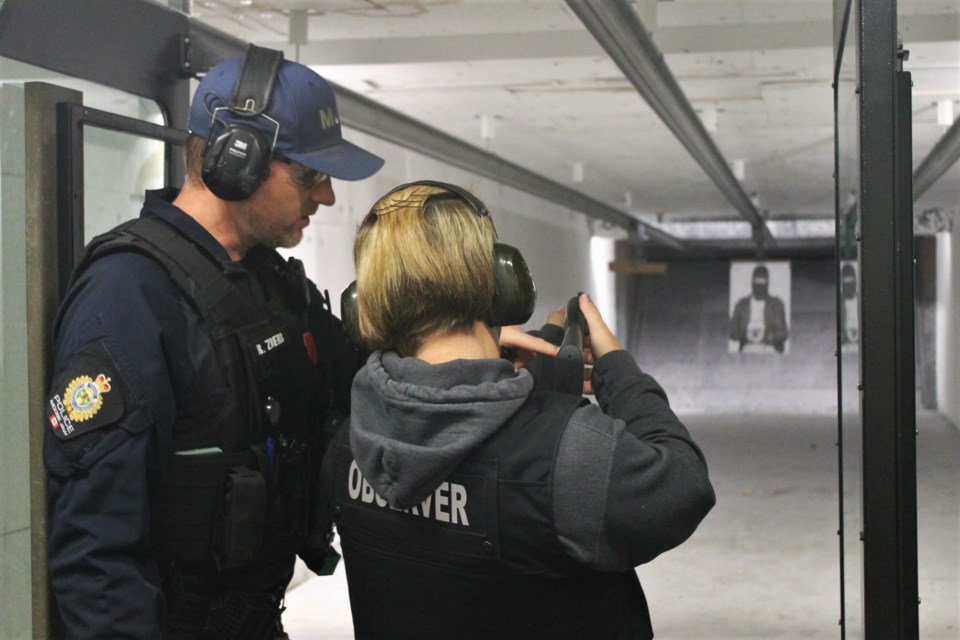 Cst. Rod Zoerb showing Community Police Academy attendee Sherry Martens-Spearman how to fire the standard-issue pump-action rifle.