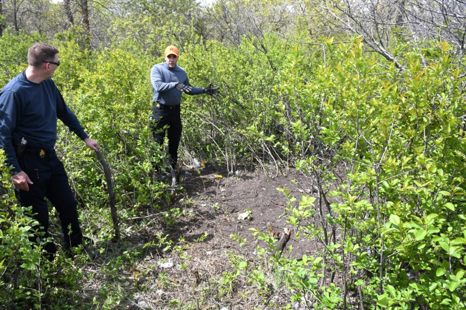 Cpl. Craig Park (left) and Const. Brendan Sanford (right, gesturing) show the site where the body was found.