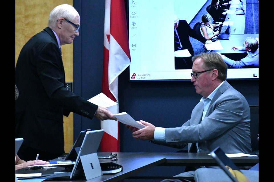 Clive Weighill, a spokesman for Canadian software company Forrest Green, gives Mayor James Murdock information about a new crime-fighting program, during the police board meeting.