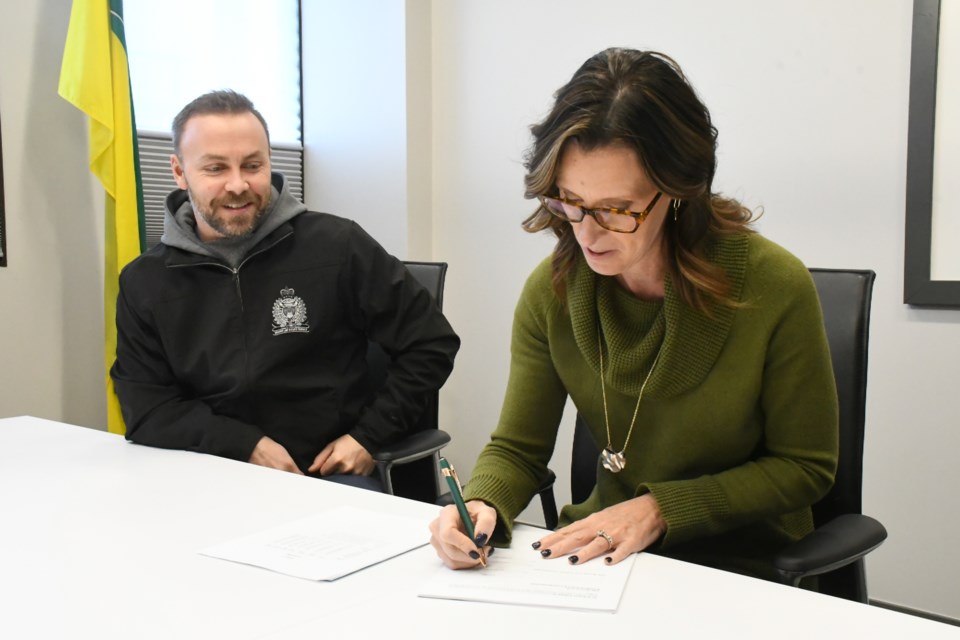 Commissioner Dawn Luhning, chairwoman of the police board (right), signs the new collective bargaining agreement while Const. Kyle Cunningham watches. Photo by Jason G. Antonio 