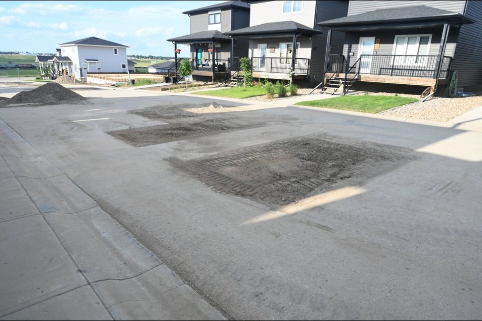 Holes cut in the roadway to allow replacement of service connections