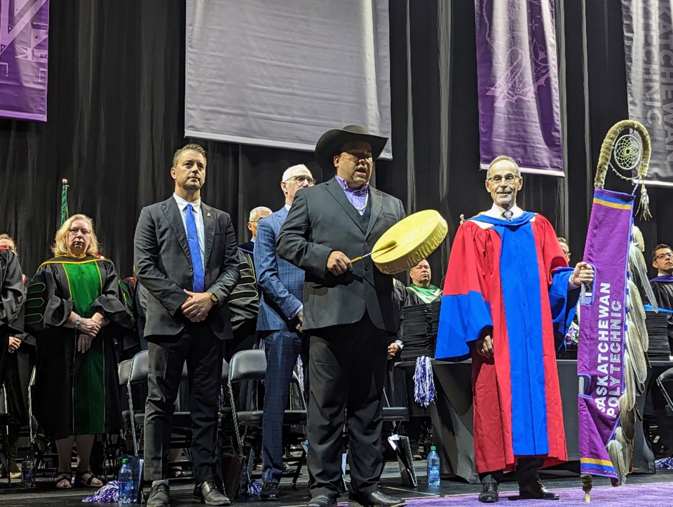 dr-larry-rosia-holds-the-eagle-staff-as-aaron-tootoosis-sings-an-honour-song-for-the-2023-sask-polytech-moose-jaw-graduates