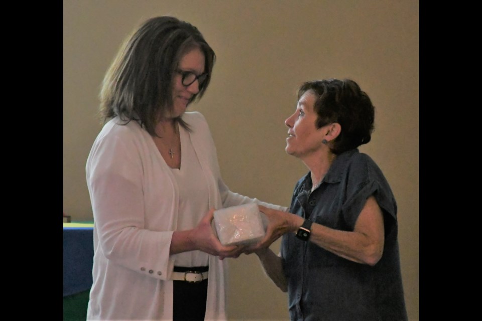Jodie Bzdel receives a gift from board chair Joann Blazieko during the final board meeting of the year. Bzdel had been the division's religion consultant for five years and was returning to the classroom. Photo by Jason G. Antonio
