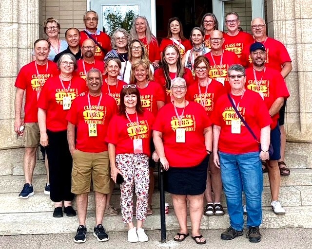 Former classmates stand together on the front steps of Central Collegiate, revisiting the school where their shared journey began over 40 years ago.