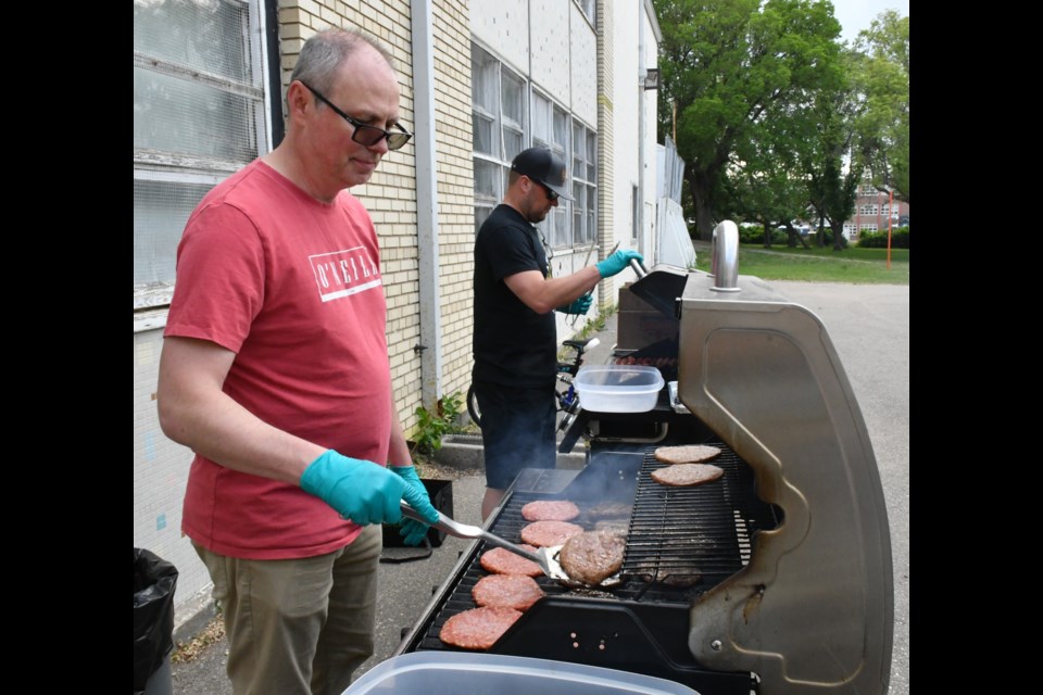Alain Simoneau and Matt Crocker cook hamburgers and hotdogs during the farewell event. Photo by Jason G. Antonio