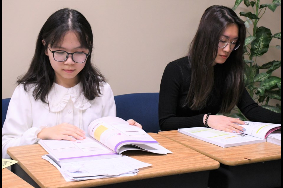 Patty Mohe and Hannah Gao look over some of their homework in their classroom, after a luncheon celebrating the grand opening of A&L Royal Academy on Oct. 10. Photo by Jason G. Antonio