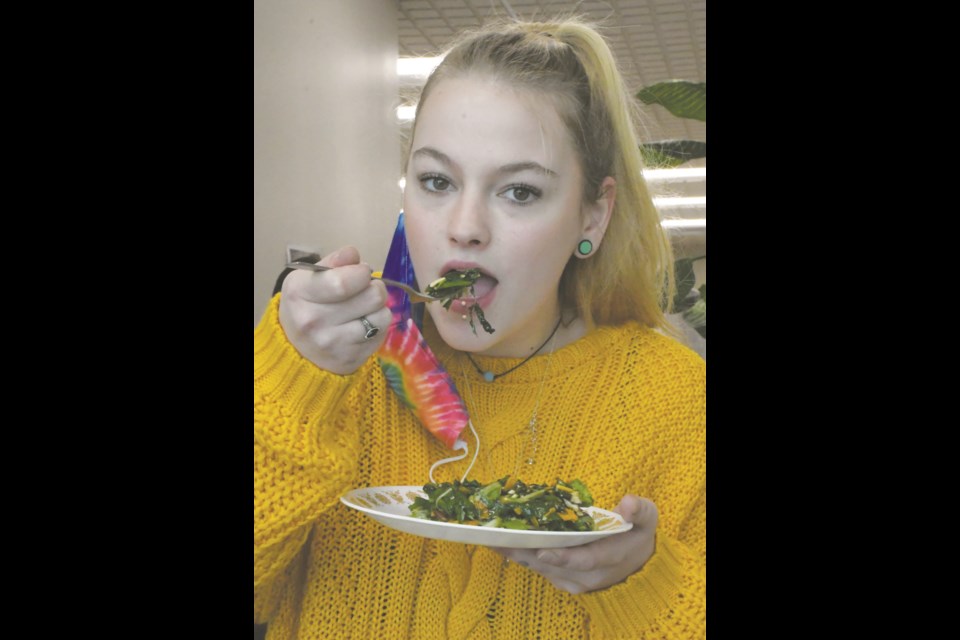 Trinity Morrissette, a Grade 11 student at Phoenix Academy, digs into a salad composed of the produce that the school grew as part of an indoor garden project. Photo by Jason G. Antonio 