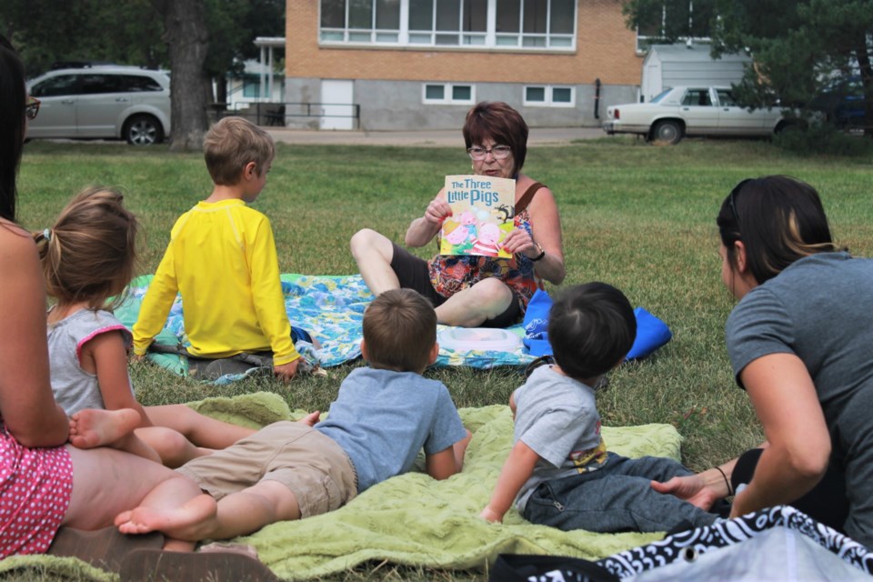 Christine Boyczuk reads “The Three Little Pigs” to a group of kids in Elgin Park on Wednesday morning.