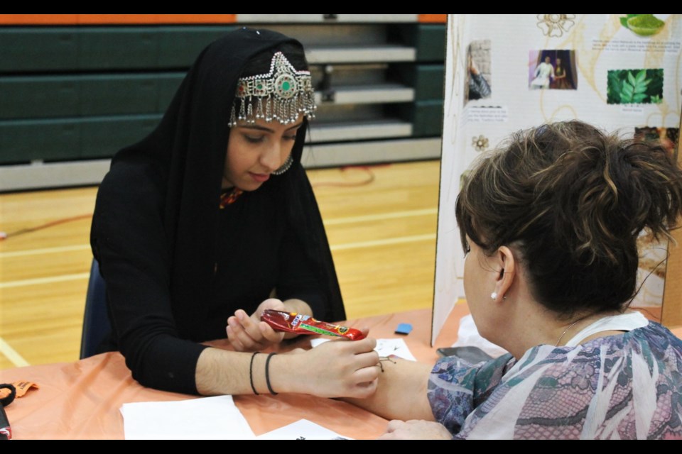 Nazish Ullah carefully drawing an intricate henna design at the Afghanistan booth. 