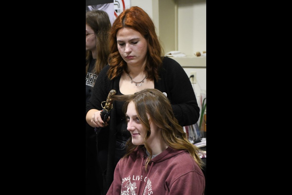 Makenna Nogue (standing) with Elite Hairstyling and Esthetics Training Centre styles the hair of a high school student. Photo by Jason G. Antonio