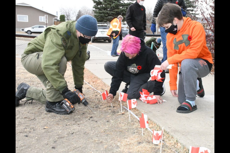 Sgt. Patrick Porter from 15 Wing helps Sunningdale School students Jaxon Weston and Reid Yeroschak plant flags to honour Canadians who died fighting in Afghanistan. Photo by Jason G. Antonio