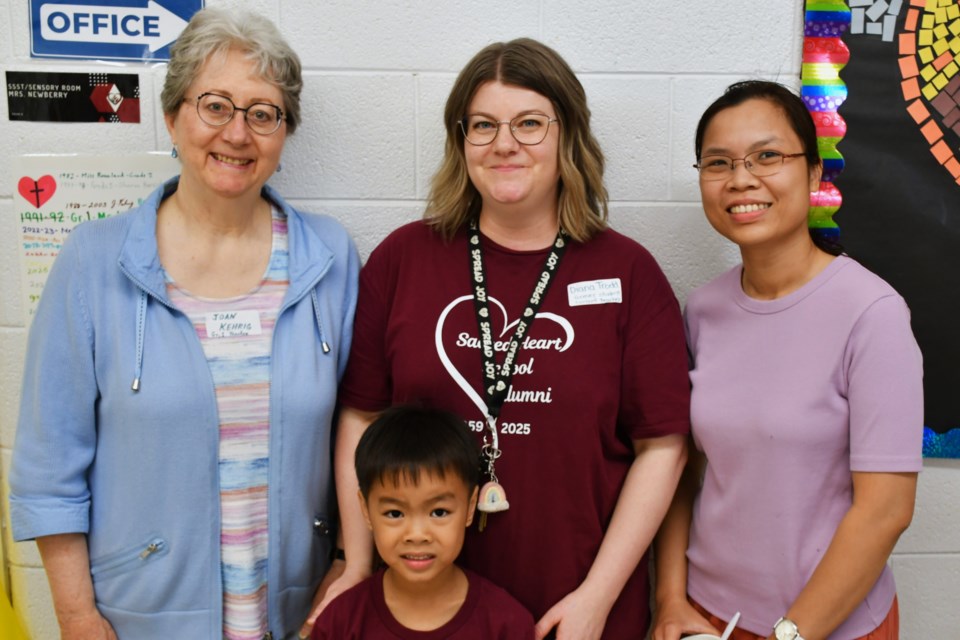 Former Grade 1 teacher Mrs. Kehrig (left), current Kindergarten teacher Diana Trodd (centre), a current student (front), and his mother (right) gather outside the former Grade 1 classroom during the school’s farewell open house on June 14.