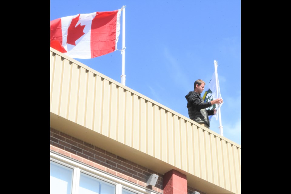 A school custodian at Riverview Collegiate attaches the Treaty 4 flag to the pole. Photo by Jason G. Antonio