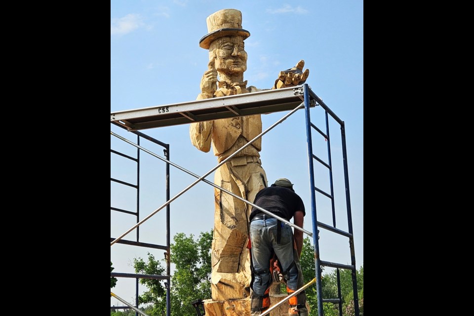 Sculptor Darren Jones works on his latest Mortlach carving — a towering wood rendition of Tragically Hip frontman Gord Downie — near the village entrance last week.