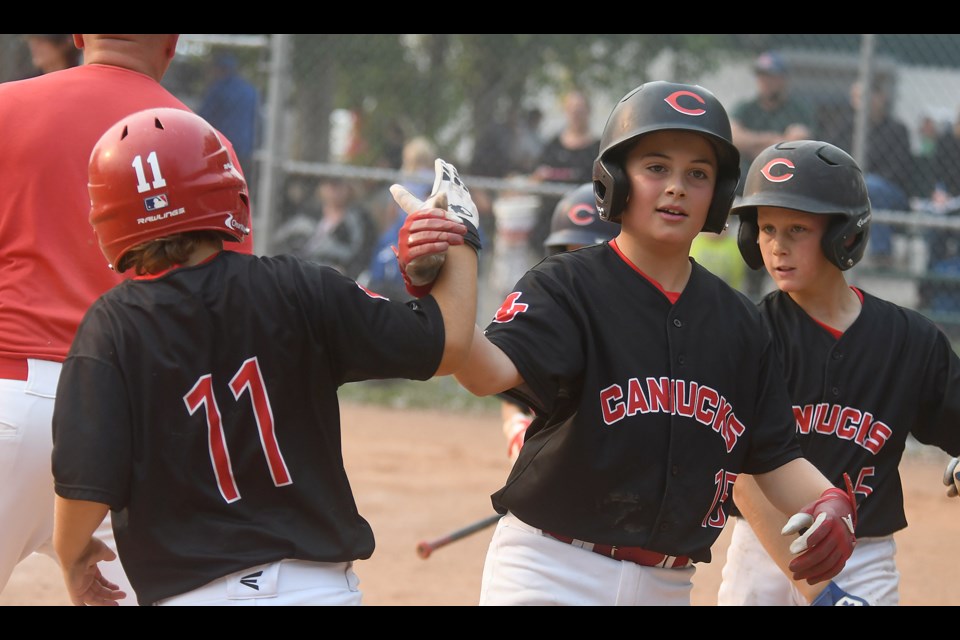 Evan Audette celebrates with teammates after scoring a run for the 11U AA Canucks.
