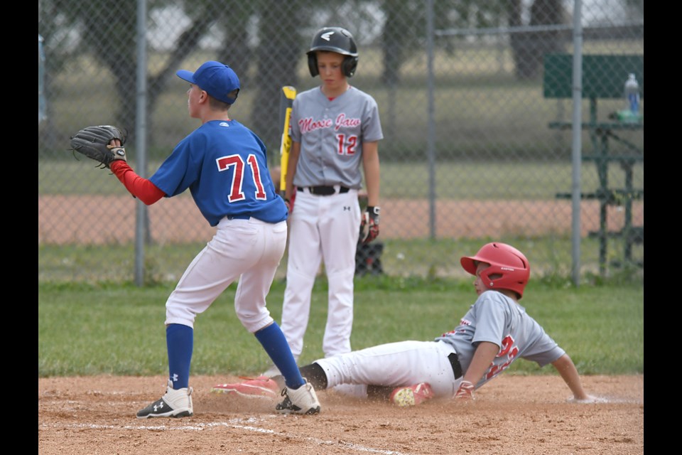 Kaison Skeoch slides home with the Canucks’ ninth run on Saturday as Karsen Pruden looks on.