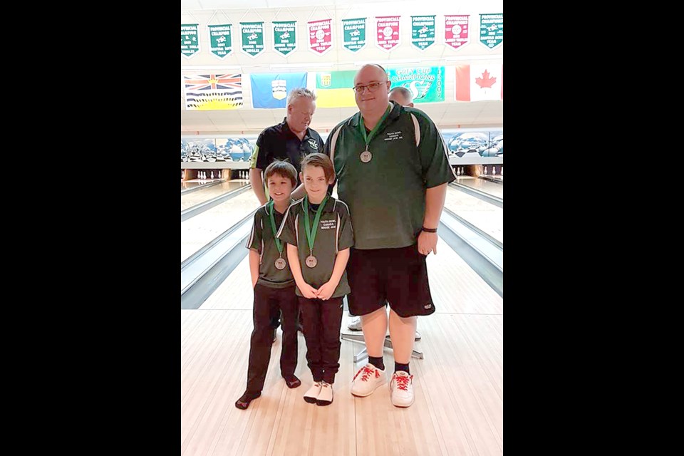 Moose Jaw’s Marcus Robinson and Parker Minchin with coach Tom Montgomery after winning their provincial silver medal.