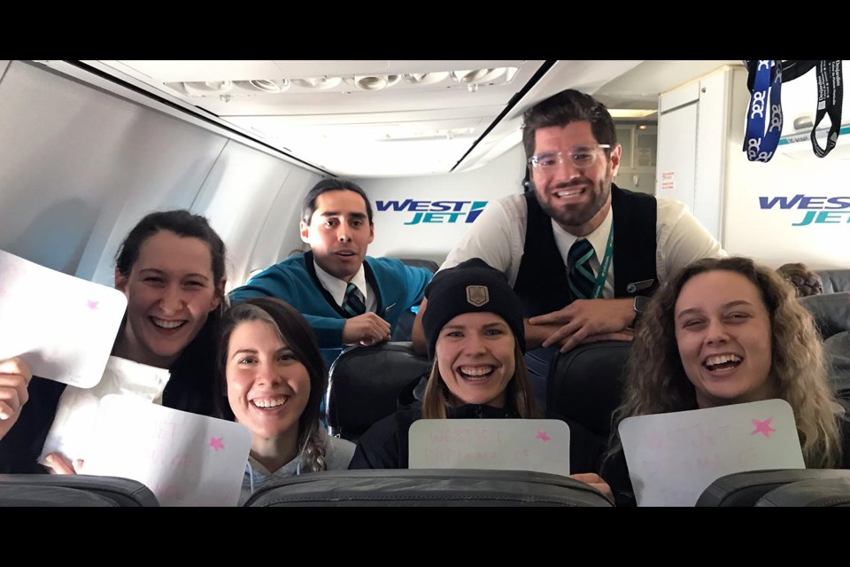 Rebecca Garner, Kirsty Kindrachuk, Ashley Erickson and Elicia Weibe pose with their ‘diplomas’ with WestJet fight attendants. Briercrest.ca photo