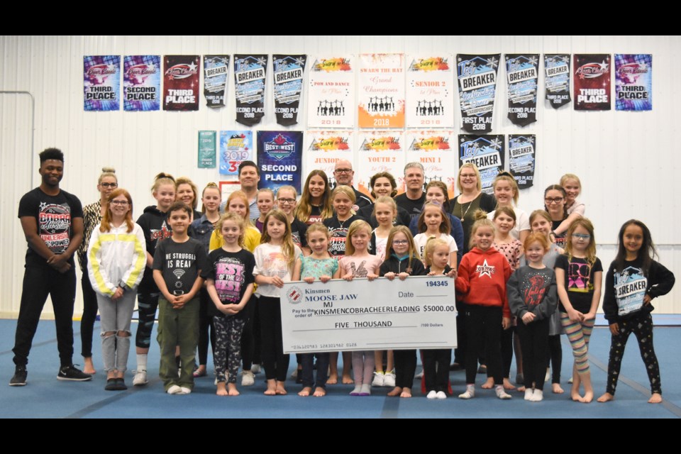Members of the Moose Jaw Kinsmen Cobra Cheerleading Club gather for a group photo with Kinsmen Cory Olafson and Dave Stevenson after receiving the first sponsorship installment of $5,000 on Friday night.