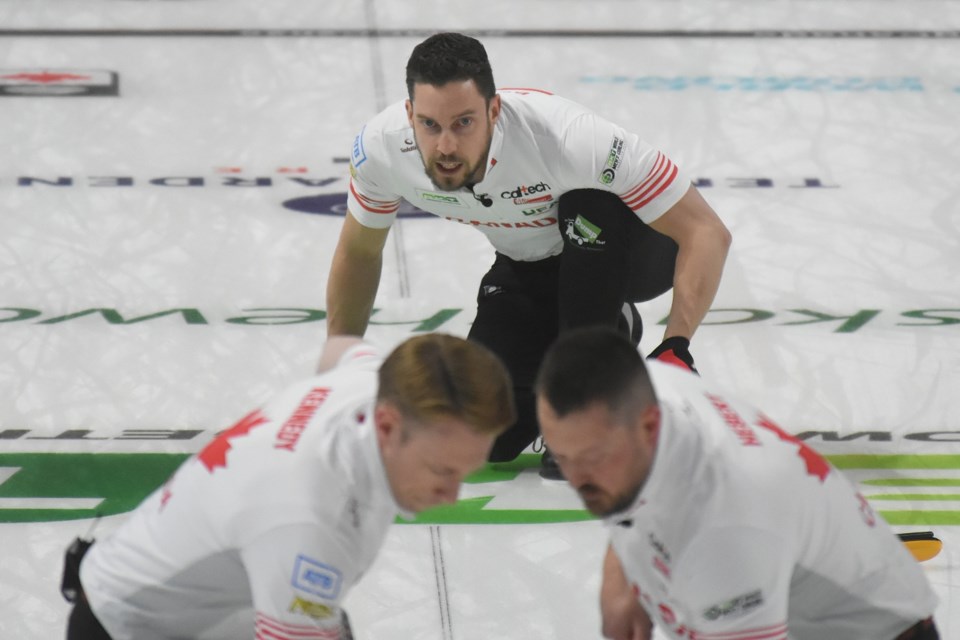 Canada’s Brett Gallant watches the line on a shot as Marc Kennedy and Ben Hebert sweep during their opening game against Japan. 
