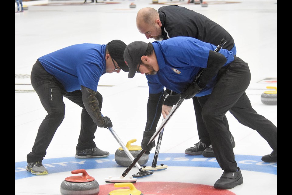 Moose Jaw skip Skip Cpl Jonathan Benson (front right), lead Capt. Jean Doyon (front left) and third Master Cpl. Jay McLellan sweep a shot into the house.