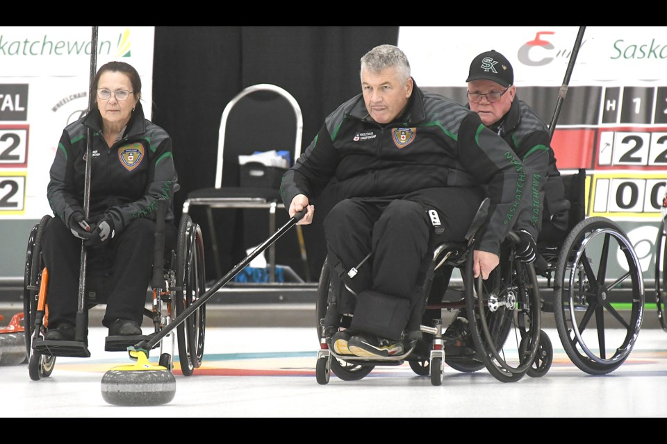 Sask 2’s Stewart McKeown throws as Russel Whisitt holds and Sheryl Pederson watches the play.