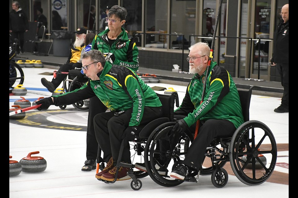 Team Canada member Gil Dash sends a shot down ice as Moose Gibson holds and Saskatchewan 1 coach Lorraine Arguin looks on during Sunday’s practice session.