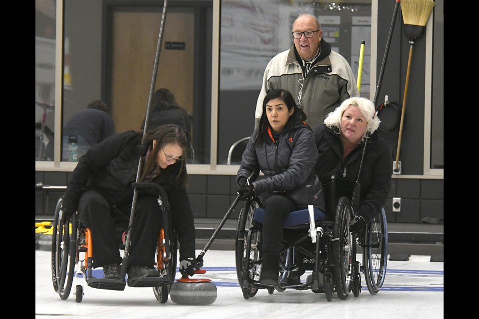 Team Sask veteran Sheryl Pederson helps set up wheelchair curling newcomer Zahra Ehsani’s shot as fellow rookie Tara-Lee Hess and coach Lloyd Thiele look on.