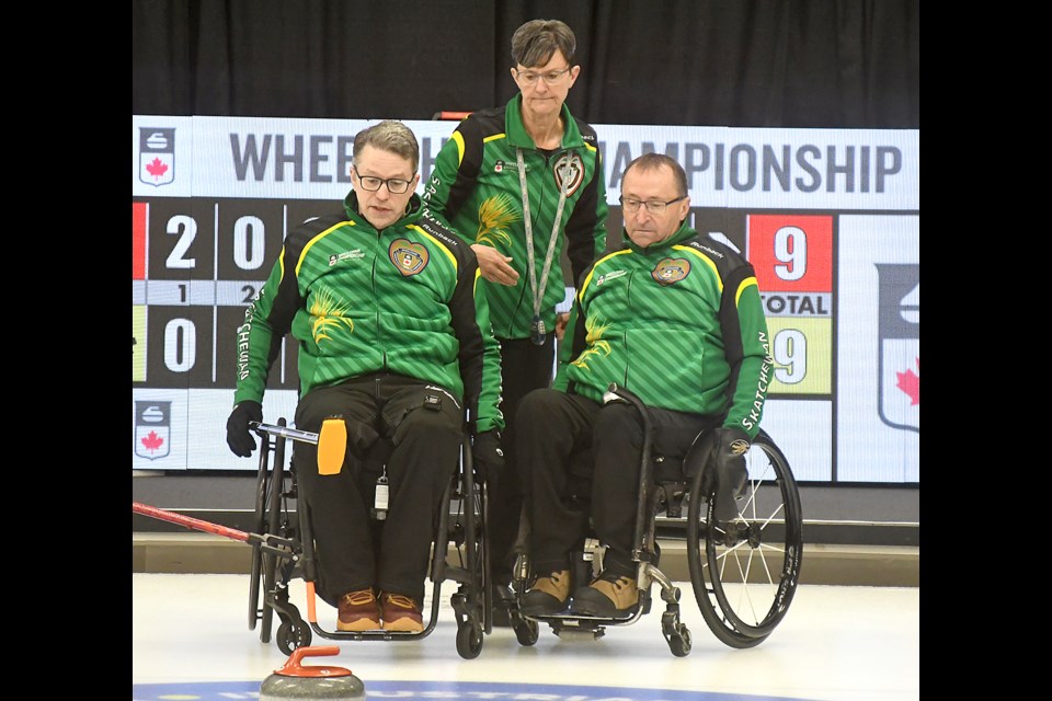 Saskatchewan 1 coach Lorraine Arguin goes over strategy with skip Gil Dash and second Darwin Bender during the extra end against Ontario 1.