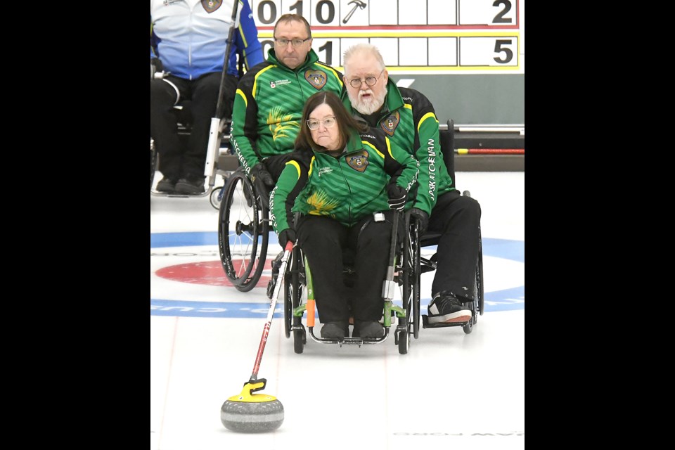 Sask 1 third Marie Wright throws her second shot of the eighth end as Moose Gibson holds and Darwin Bender looks on Wednesday afternoon.