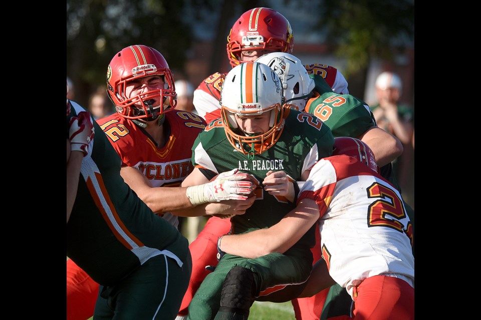 Peacock quarterback Kyle Yamniuk runs into Cyclones tacklers Jared Booth (12) and Layne Johnson.