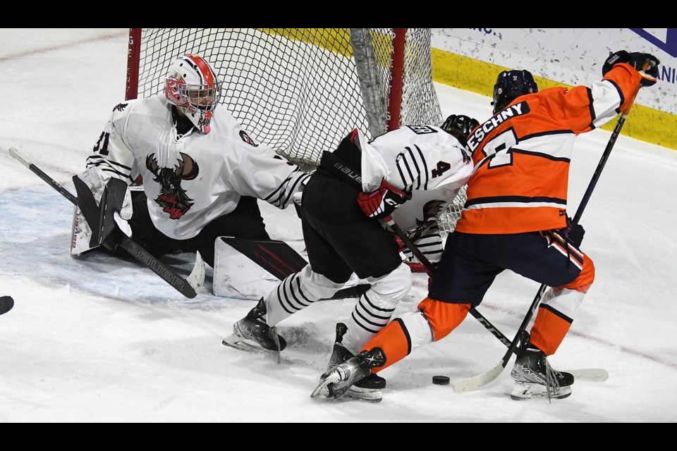 Saskatoon Blazers forward Cole Reschny attempts to get a shot off on Warriors goaltender Ryan Bain as defenceman Caleb Potter ties him up at the side of the net.
