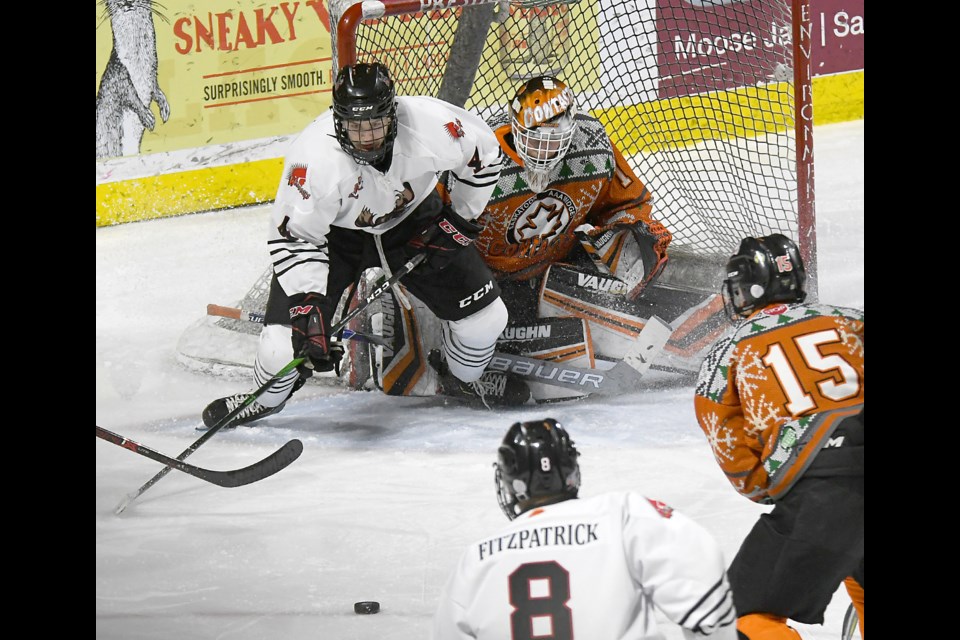 Moose Jaw Warriors forward Kirk Mullen and Saskatoon Contacts goaltender Ethan Chadwick keep their eye on the puck.