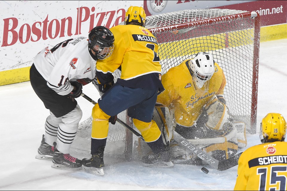 The Warriors’ Ben Wourms-Rowe attempts to knock the puck past Legionnaires goaltender Jacob Herman as Swift Current’s Ryan McLeary covers the play.