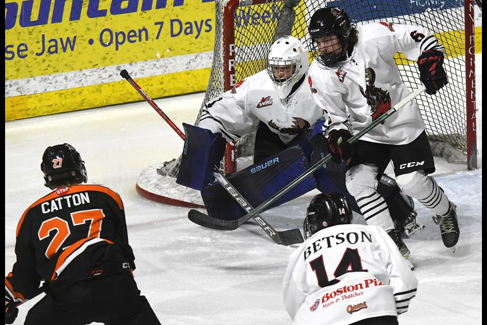 Warriors goaltender Ethan Fechter is joined by Ryder Knutson and Blake Betson in keeping a close eye on Berkly Catton during second-period action.