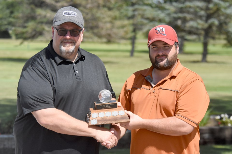 Moose Jaw city men’s golf champion Nick Lepine accepts the championship trophy from The Sweet Spot general manager Carlo Berardi.