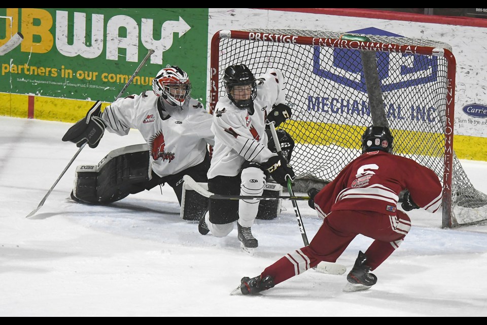 Moose Jaw Bantam AA Warrior defender Ty Pratte attempts to block a shot by Regina’s Carson Birnie as goaltender Judah Goodnough scrambles back into position.