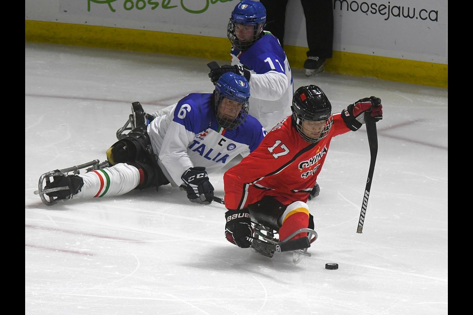 China’s Shen Yi Feng carries the puck out of a scrum with Italy’s Gian Luca Cavaliere (6) and Nils Larch.