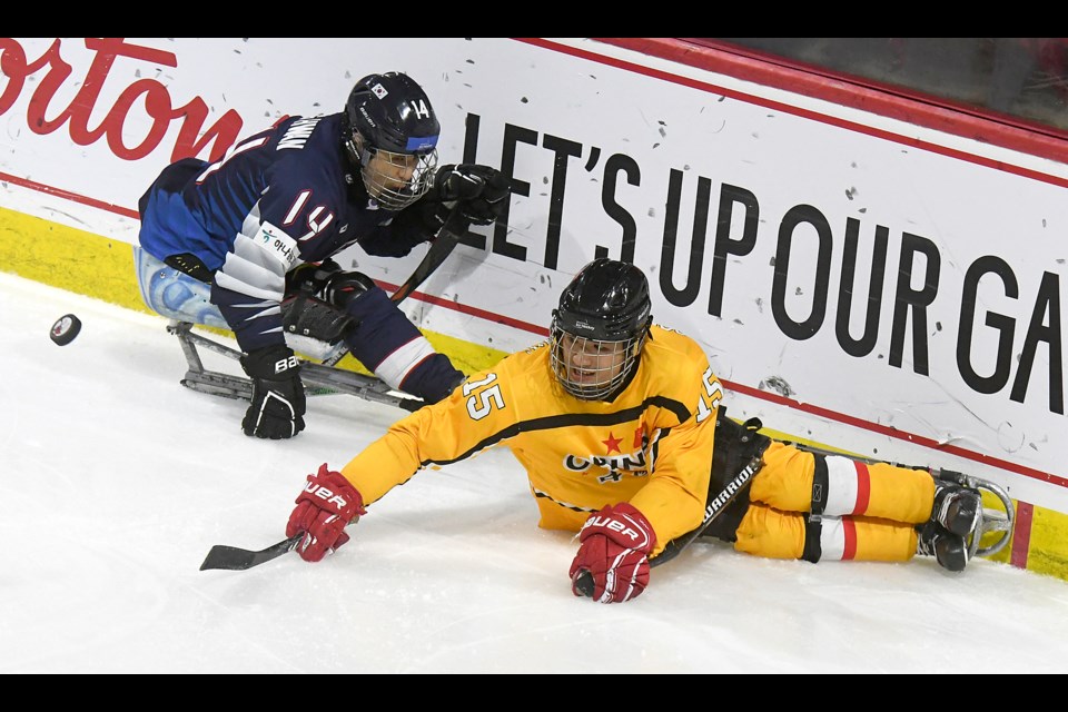 China’s Song Xiao Dong flips a puck to the front of the Korea net ahead of Jung Seung Hwan.