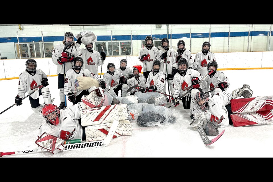 The Moose Jaw U13 AA Warriors gather for a team photo with the warmth bundles thrown on the ice after their first goal.
