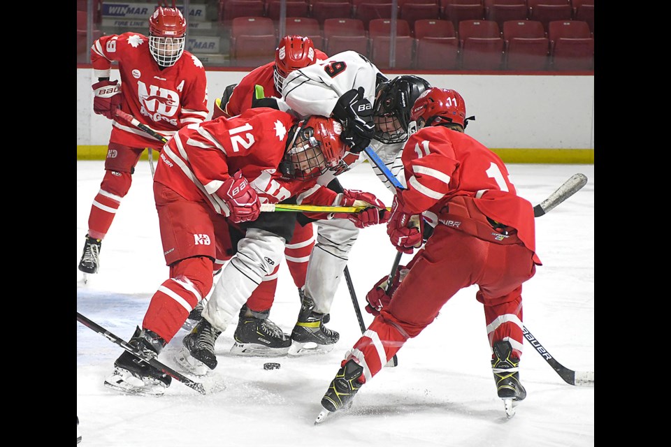 Warriors forward Noah Osiowy battles Notre Dame defenders for the puck in front of the net.