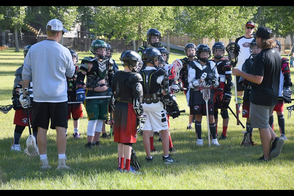 Players listen to the layout of a drill during the field lacrosse camp Thursday.