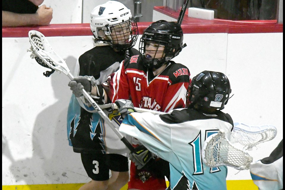 Chaysen Seiferling of the Mustangs 1 attempts to break through the check of a pair of QCMBL Reapers.