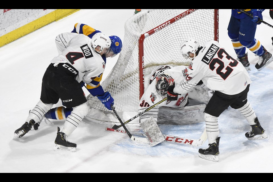 Jett Woo and Tristin Langan help goaltender Brodan Salmond cover up the puck during regular season action against Saskatoon.